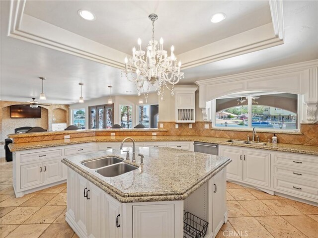 kitchen featuring ceiling fan with notable chandelier, plenty of natural light, an island with sink, and sink