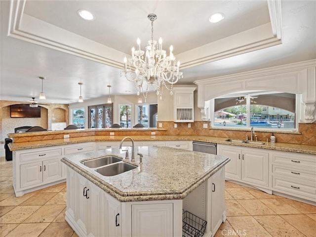 kitchen featuring stainless steel dishwasher, a raised ceiling, decorative backsplash, and a sink