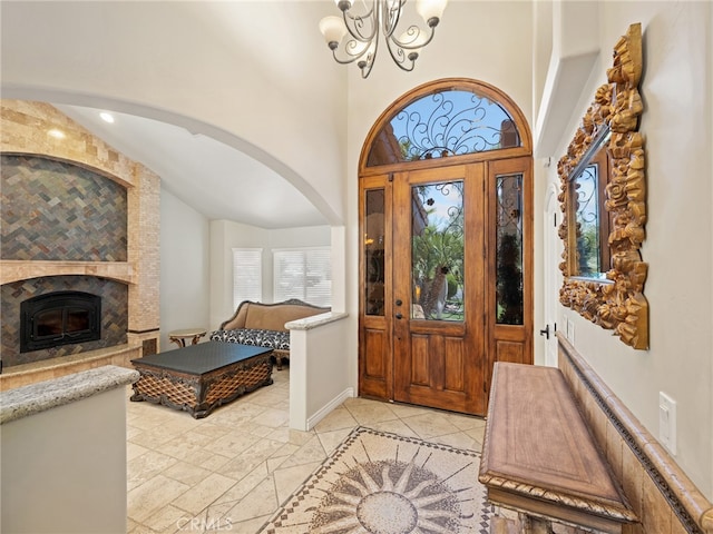 entrance foyer featuring a fireplace, high vaulted ceiling, and a chandelier