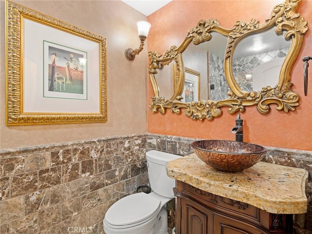 bathroom with vanity, tile walls, toilet, and a wainscoted wall