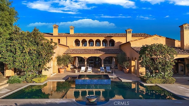 rear view of house featuring a swimming pool with hot tub and a patio