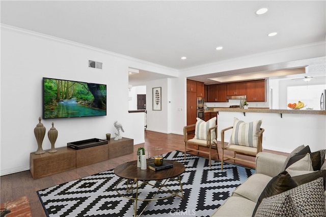 living room with ornamental molding, dark wood-type flooring, and ceiling fan