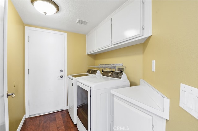 washroom featuring dark hardwood / wood-style floors, a textured ceiling, cabinets, and washing machine and clothes dryer