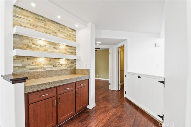 bar featuring dark wood-type flooring, light stone counters, and tasteful backsplash