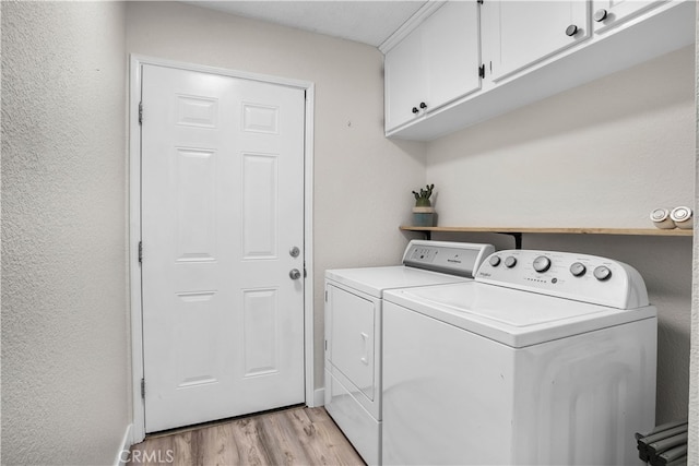 washroom with light hardwood / wood-style floors, separate washer and dryer, and cabinets