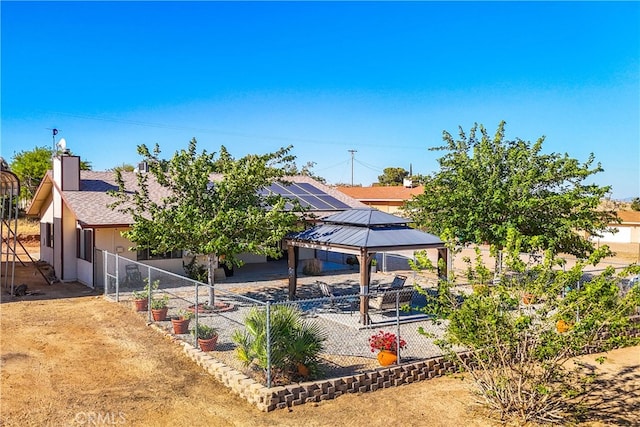 rear view of property featuring a gazebo and solar panels