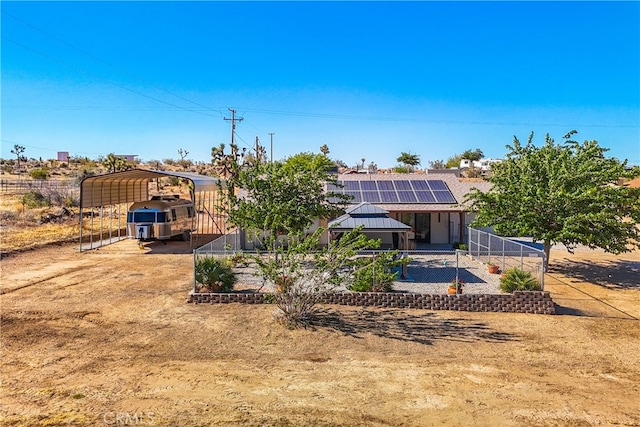 back of house with solar panels and a carport