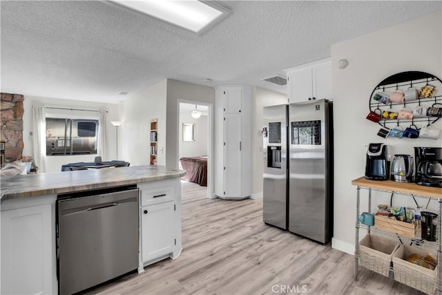 kitchen with white cabinetry, appliances with stainless steel finishes, light hardwood / wood-style flooring, and a textured ceiling