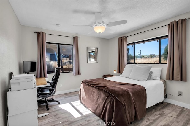 bedroom featuring ceiling fan, light hardwood / wood-style flooring, and a textured ceiling