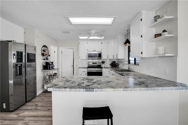 kitchen featuring ceiling fan, wood-type flooring, sink, kitchen peninsula, and stainless steel appliances