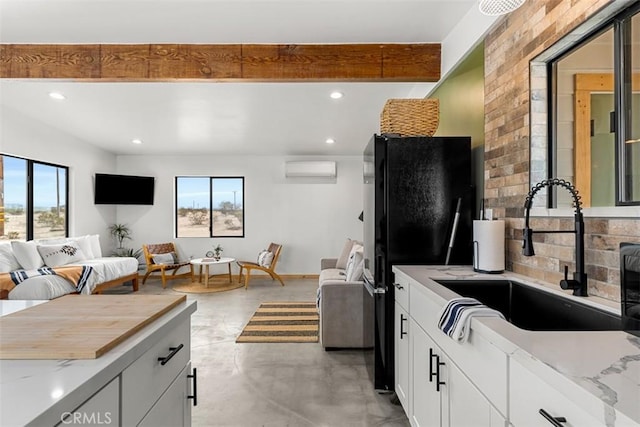 65154 Hoover Rd, Joshua Tree, CA 92252 - kitchen with freestanding refrigerator, an AC wall unit, finished concrete flooring, open floor plan, and white cabinetry
