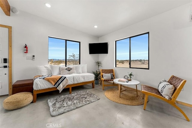 bedroom featuring beamed ceiling, concrete floors, and multiple windows