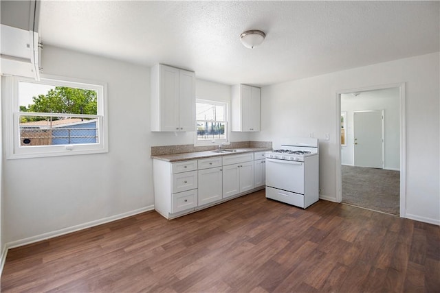 kitchen with white cabinets, white gas range, dark wood-type flooring, and a wealth of natural light