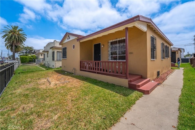 view of side of home featuring a yard, fence, and stucco siding