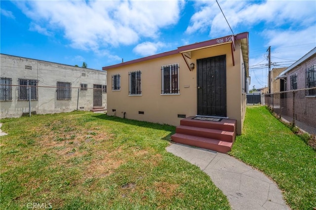 back of property featuring crawl space, fence, a lawn, and stucco siding