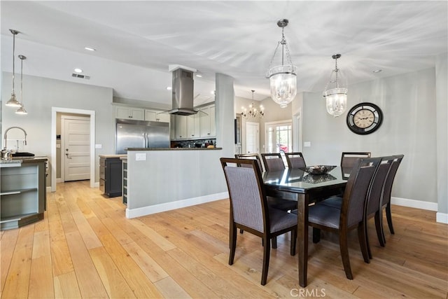 dining room with a notable chandelier, light hardwood / wood-style floors, and sink