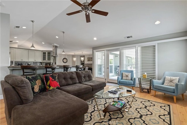 living room featuring light hardwood / wood-style floors, vaulted ceiling, and ceiling fan