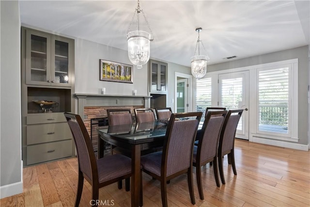 dining space with light hardwood / wood-style floors, a fireplace, and a chandelier