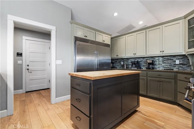 kitchen featuring backsplash, gray cabinetry, stainless steel built in refrigerator, vaulted ceiling, and butcher block countertops