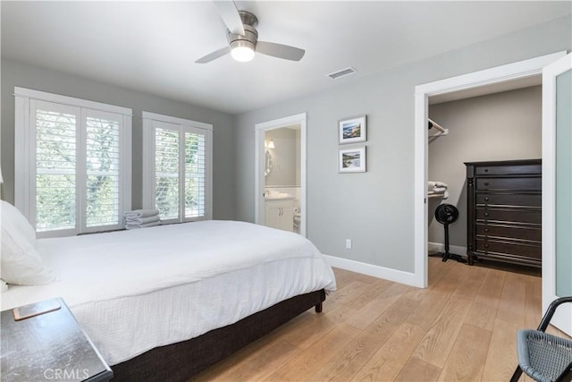 bedroom with connected bathroom, ceiling fan, light hardwood / wood-style flooring, a walk in closet, and a closet