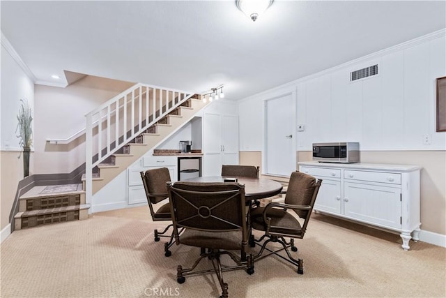 dining room with light colored carpet and crown molding