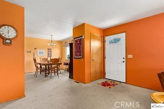 foyer with carpet flooring and an inviting chandelier