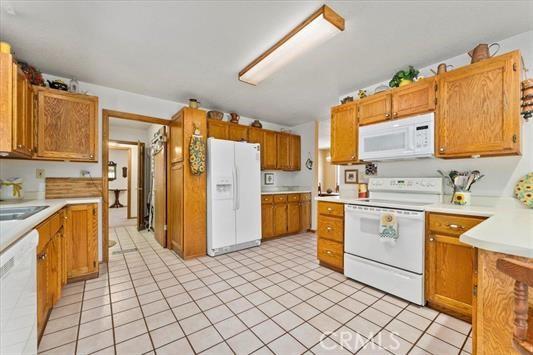 kitchen with light tile patterned floors, white appliances, and sink