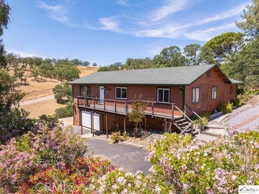 rear view of property with a wooden deck and a garage