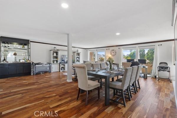 dining space with ornamental molding and dark wood-type flooring