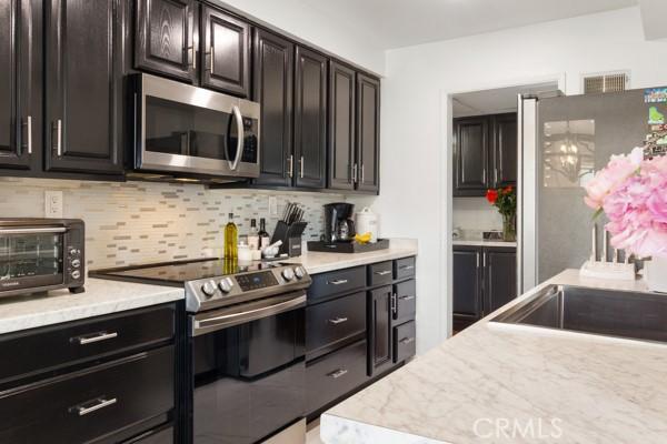 kitchen with tasteful backsplash, dark brown cabinets, and stainless steel appliances