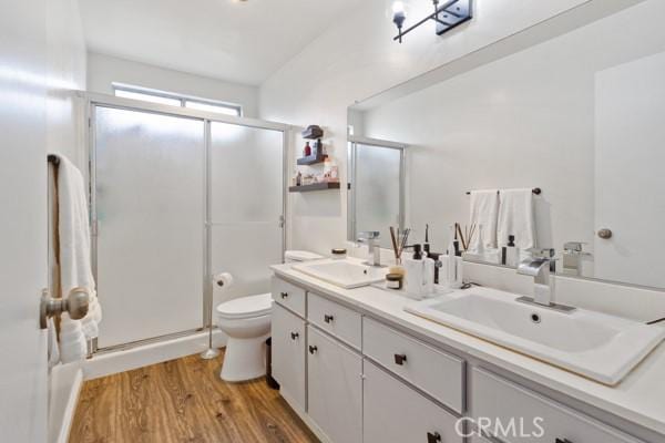 bathroom with toilet, vanity, wood-type flooring, and walk in shower