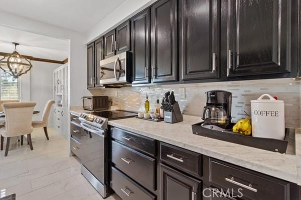 kitchen featuring hanging light fixtures, stainless steel appliances, an inviting chandelier, tasteful backsplash, and light stone counters