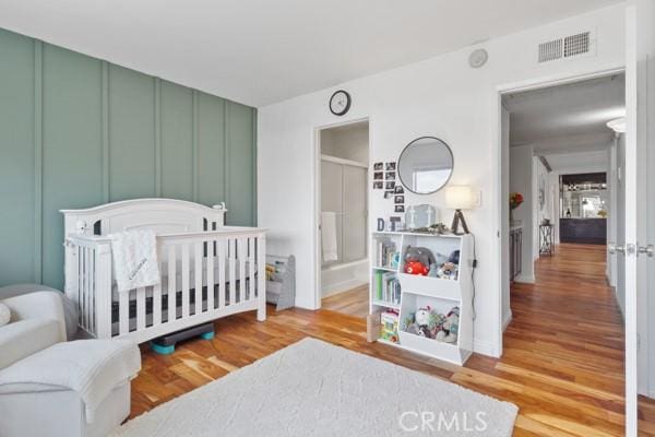 bedroom with hardwood / wood-style floors and a nursery area