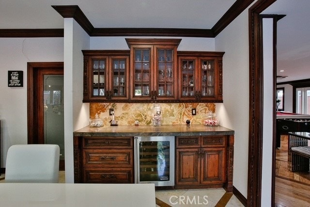 bar featuring ornamental molding, beverage cooler, tasteful backsplash, and light tile floors