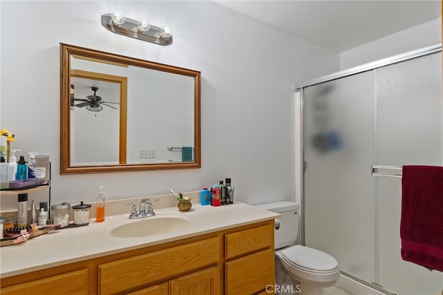 bathroom with vanity, toilet, ceiling fan, and a shower with shower door