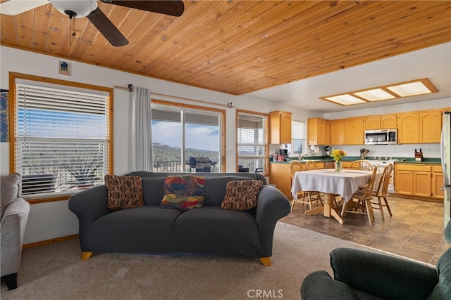 carpeted living room featuring ceiling fan and wood ceiling