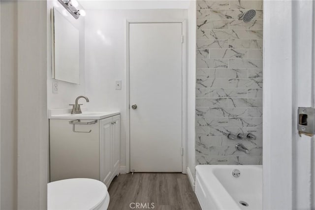 full bathroom featuring vanity, wood-type flooring, tiled shower / bath combo, and toilet