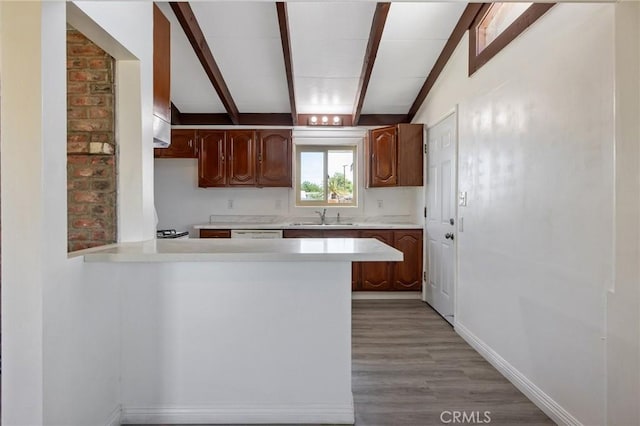 kitchen featuring kitchen peninsula, vaulted ceiling with beams, light hardwood / wood-style floors, and sink