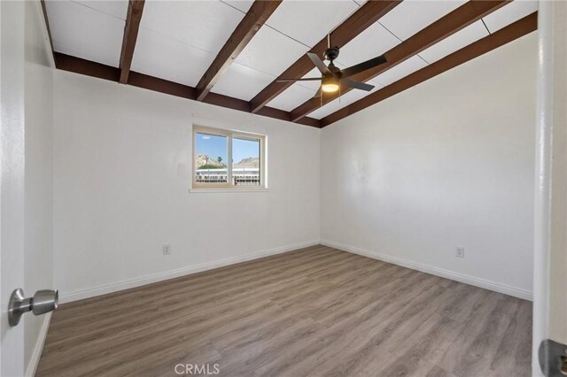 empty room featuring wood-type flooring, lofted ceiling with beams, and ceiling fan