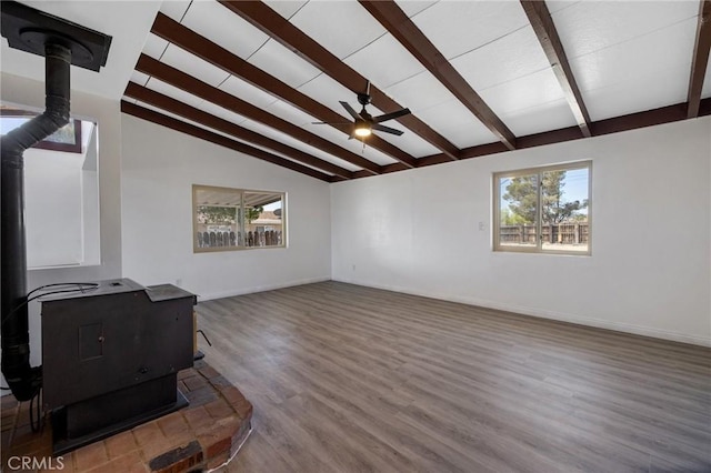 unfurnished living room featuring a wood stove, ceiling fan, lofted ceiling with beams, and wood-type flooring