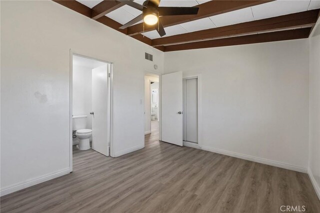 unfurnished bedroom featuring lofted ceiling with beams, ensuite bathroom, ceiling fan, and light hardwood / wood-style floors