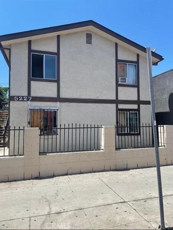 view of side of property with a fenced front yard and stucco siding