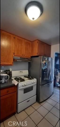 kitchen featuring stainless steel fridge, white gas range oven, and light tile flooring