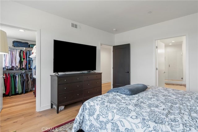 bedroom featuring light wood-type flooring, ensuite bathroom, and a closet