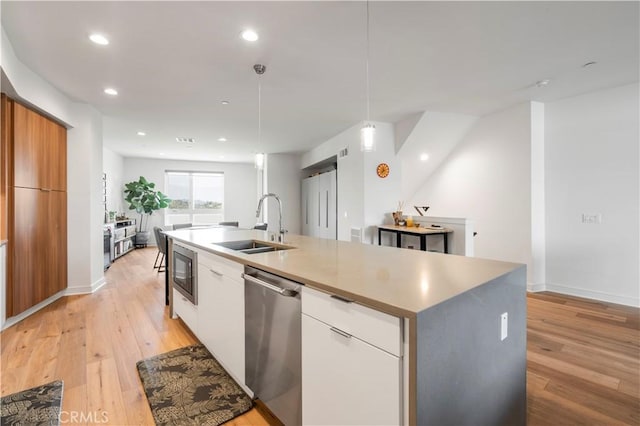 kitchen featuring pendant lighting, white cabinets, sink, an island with sink, and stainless steel appliances