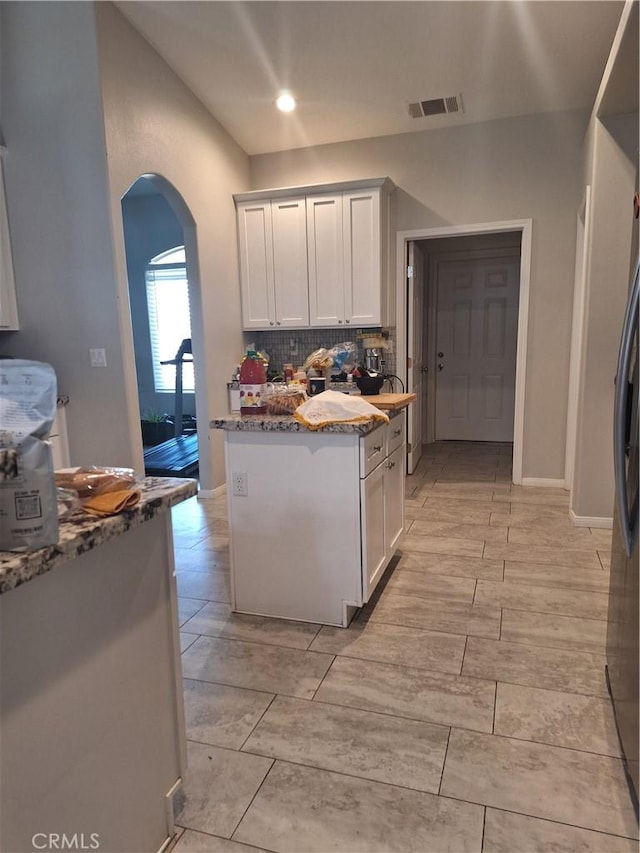 kitchen with backsplash, stone counters, and white cabinets