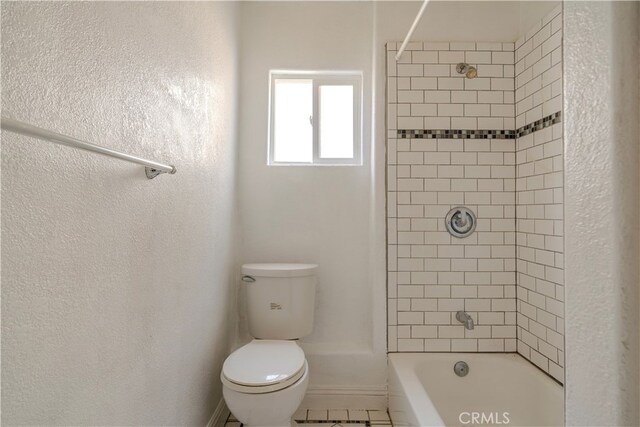 bathroom featuring toilet and tiled shower / bath