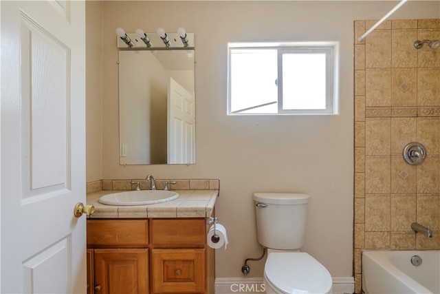 full bathroom featuring vanity, tiled shower / bath, and toilet