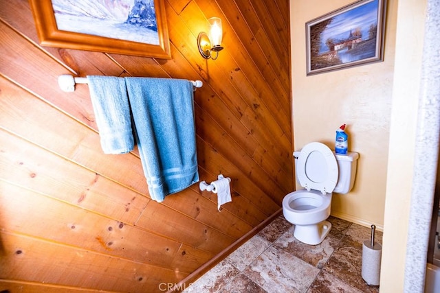 bathroom featuring toilet and wood walls