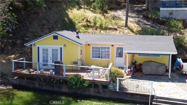 rear view of house featuring a deck with water view and french doors